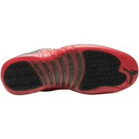 Outsole of black and varsity red Jordan 12 Retro Flu Game sneaker featuring a herringbone tread and Jumpman logo.