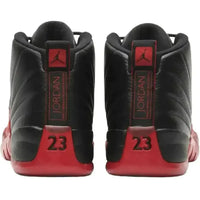 Back view of black tumbled leather Jordan 12 Flu Game sneakers with red mudguards, Jumpman logos, and 23 heel branding.